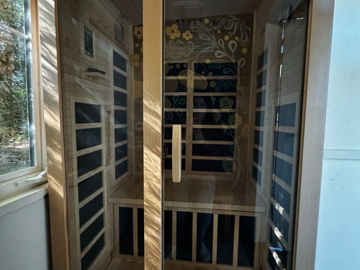 Two-person infrared sauna with glass doors on the covered deck at Minterwood Revival
